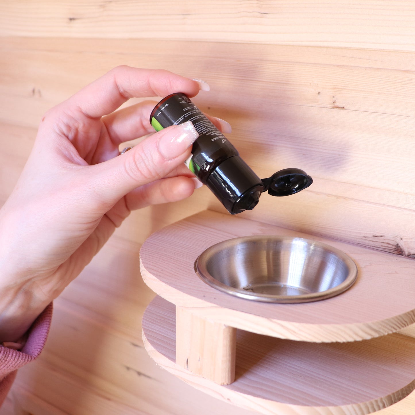 Hand holding a flashlight above a metal bowl on a wooden stand.
