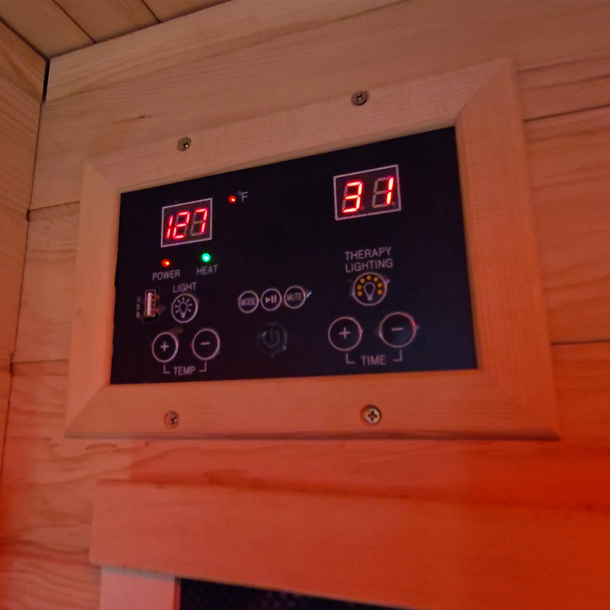 Digital control panel with temperature and time display in a wooden sauna.