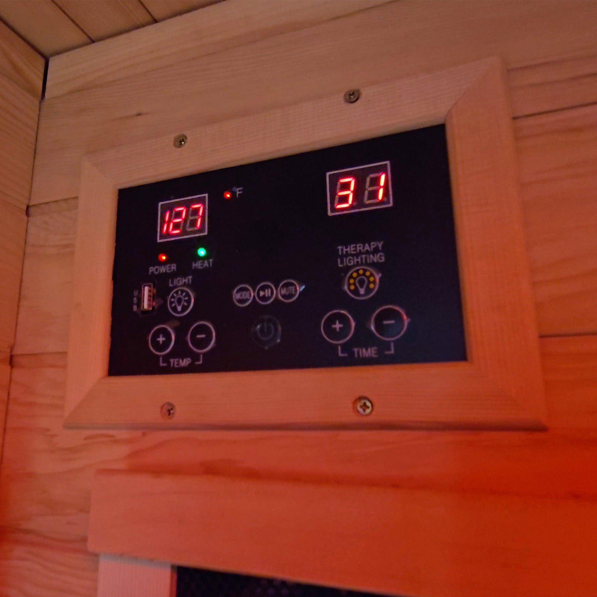 Digital control panel with temperature and time display in a wooden sauna.