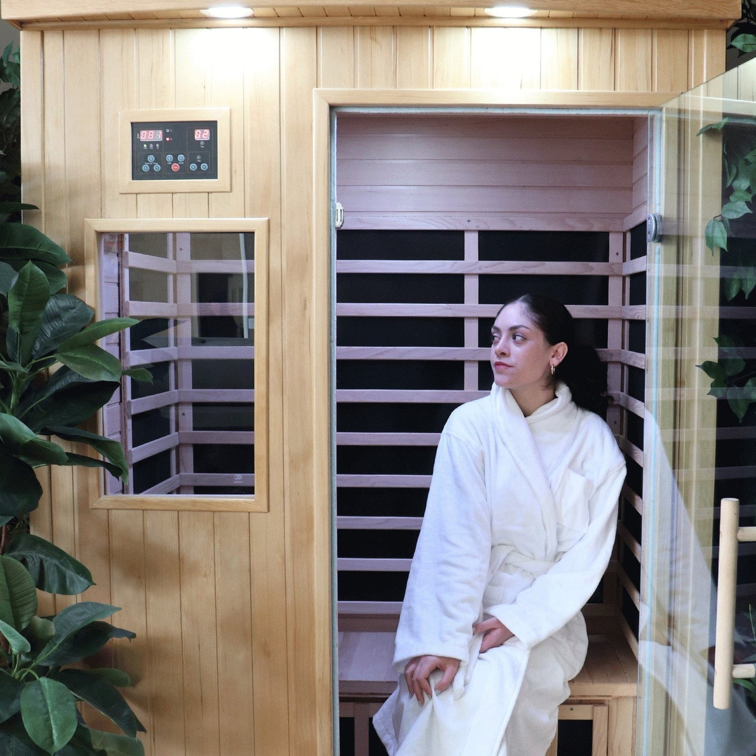 Interior view of the Tremblant 2-person hemlock infrared sauna with a woman in a bathrobe relaxing on the bench.